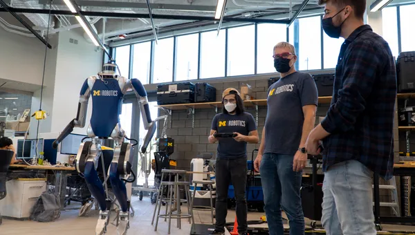 Professor Jessy Grizzle shows Victor Popa-Simil a Cassie robot with a lidar sensor on top.
