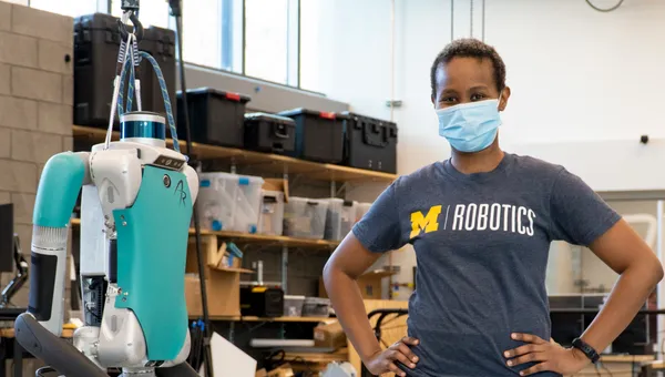 Eva Mungai stands next to a Digit, a bipedal Agility Robotics robot, in her lab.