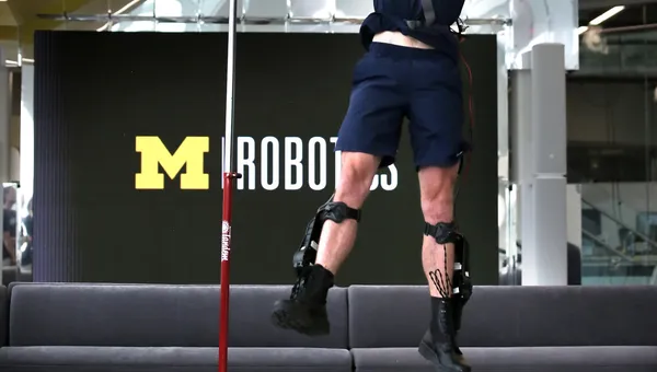 A track and field athlete jumps with the assistance of an ankle exoskeleton.