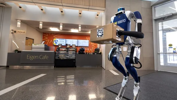A Digit bipedal robot holds a package in the lobby of the Robotics Building at the University of Michigan.