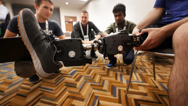 Professor Elliott Rouse, center, speaks with Kevin Best, left, a Robotics PhD, and Senthur Ayyappan, right, who works with Rouse on the Open-Source leg. The leg is being worn by first year Mechanical Engineering PhD student Andrew Seelhoff.