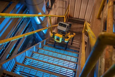 Boston Dynamics Spot robot quadruped walks up industrial staircase.