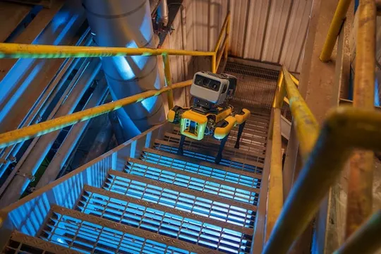 Boston Dynamics Spot robot quadruped walks up industrial staircase.