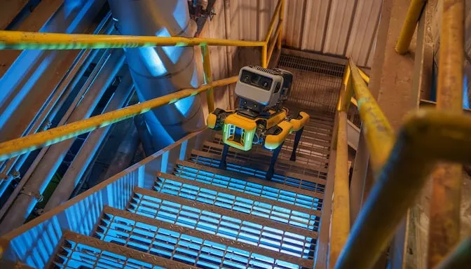 Boston Dynamics Spot robot quadruped walks up industrial staircase.