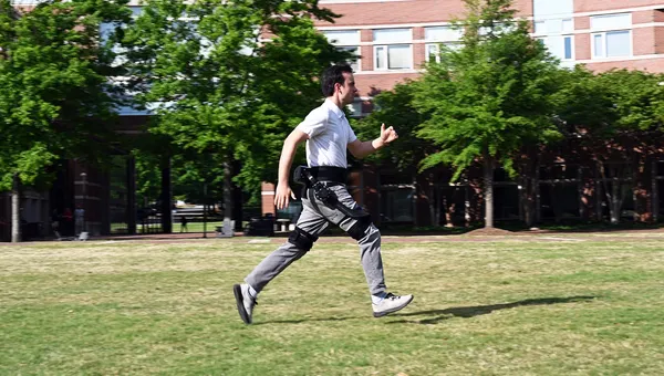 Legs of a user walking on a two-track treadmill in a lab wearing powered ankle exoskeletons.