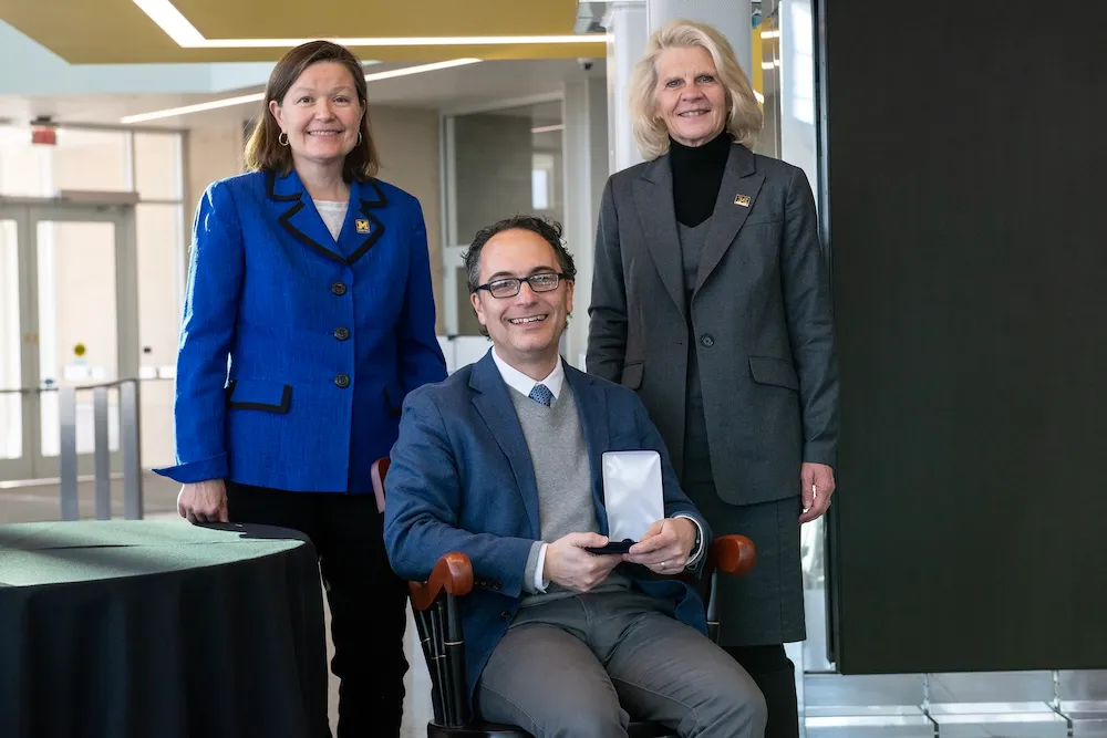 Jason Corso sits in the chair representing the professorship, with Robotics Department chair Dawn Tilbury and Dean Karen Thole behind.