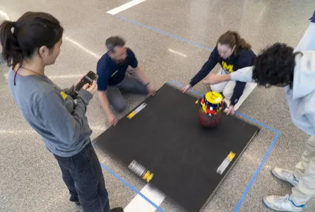 Lecturer and students test an MBot on a balancing board