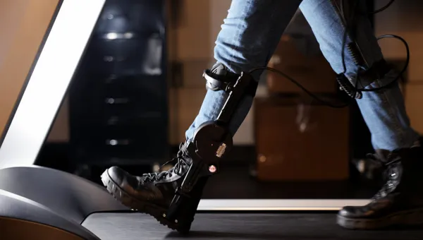 A user's legs walking with a powered ankle exoskeleton on a treadmill