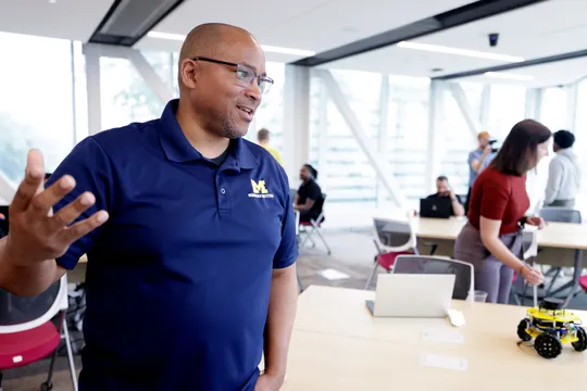 Chad Jenkins speaks with attendees at the Distributed Teaching Collaborative Summer Session at the Ford Motor Company Robotics Building.