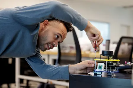 A student assembles an MBot mobile robot with a screwdriver
