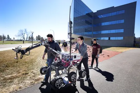 Students transport the MRover robot outside the Ford Robotics Building