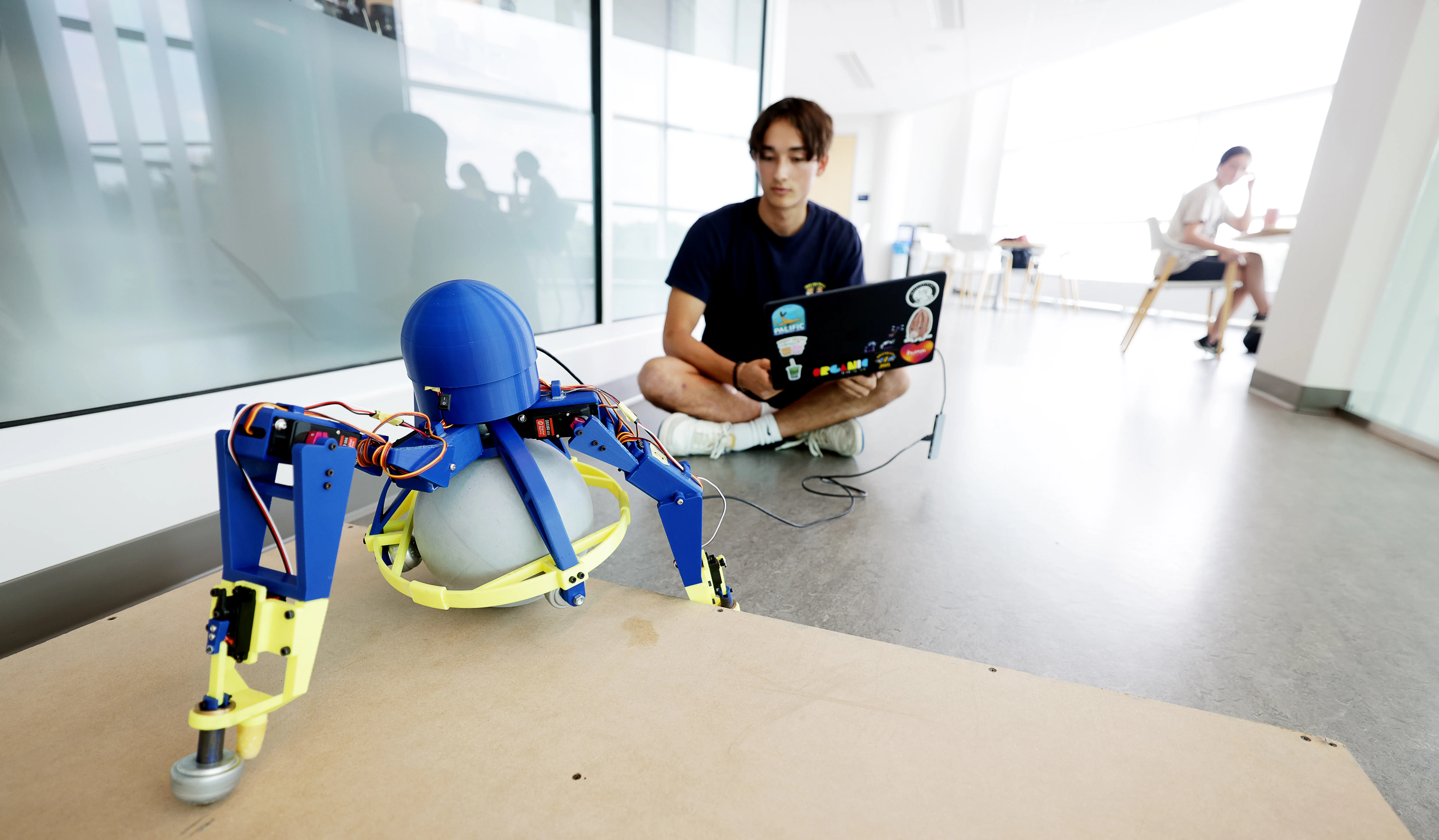 Adam Hung, Robotics undergraduate, with a tripedal robot he developed at the Ford Robotics Building.