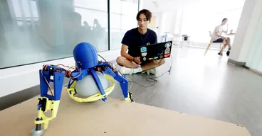 Adam Hung, Robotics undergraduate, with a tripedal robot he developed at the Ford Robotics Building.