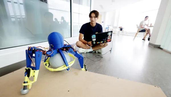Adam Hung, Robotics undergraduate, with a tripedal robot he developed at the Ford Robotics Building.