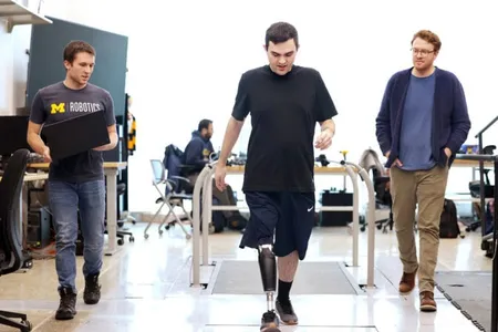 Three men walk through a lab with a treadmill built into the floor behind them. In the center, Seelhoff wears a prosthetic leg that stores its electronics inside a slim calf-shaped casing. On the left, Kevin carries an open laptop computer.