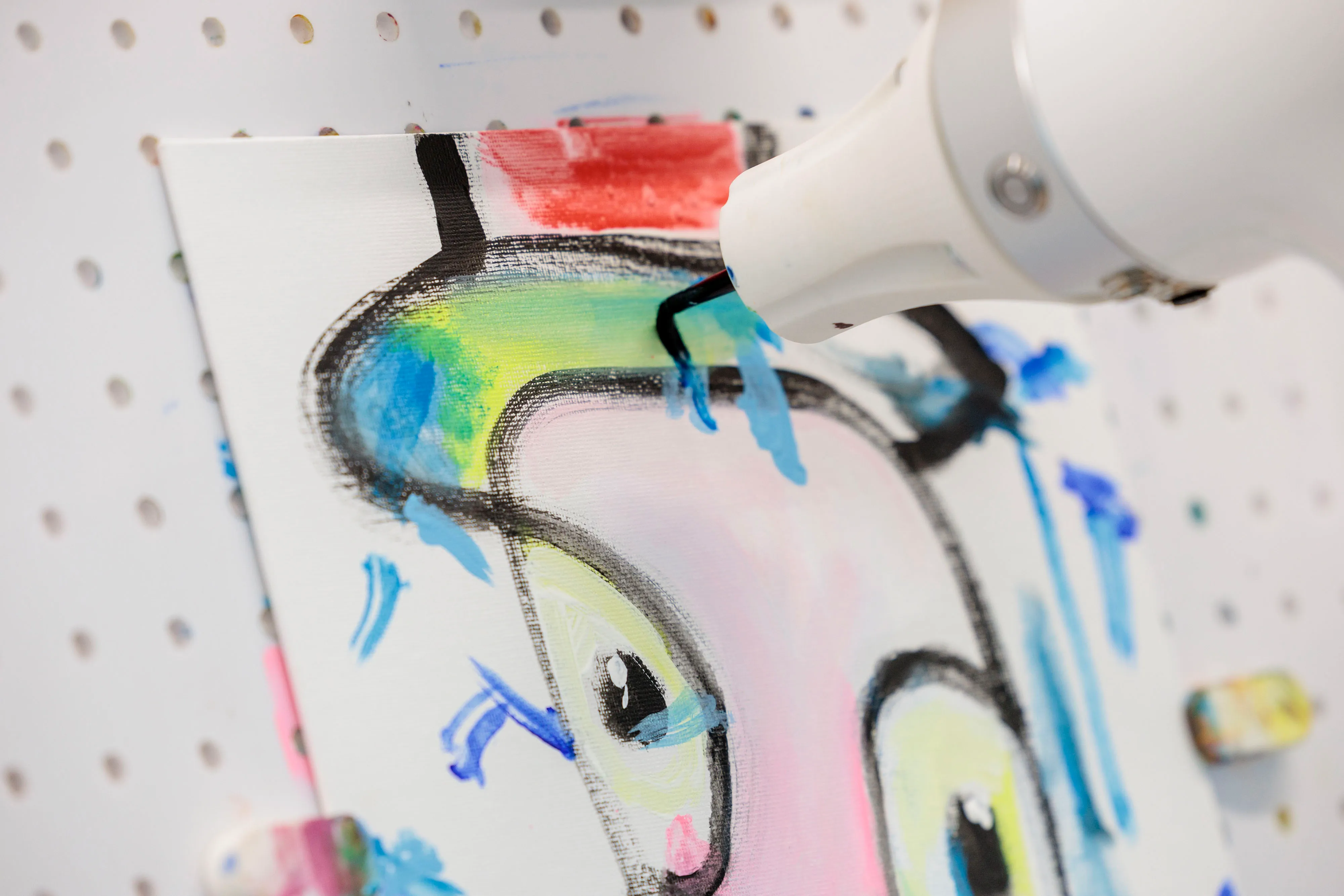 The robot applies brush strokes to a painting it works on with an abstract artist.