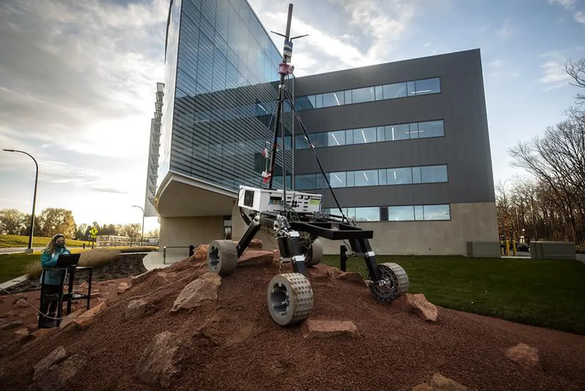 A Michigan Mars Rover team member drives the rover over the Mars Yard outside the Robotics Building