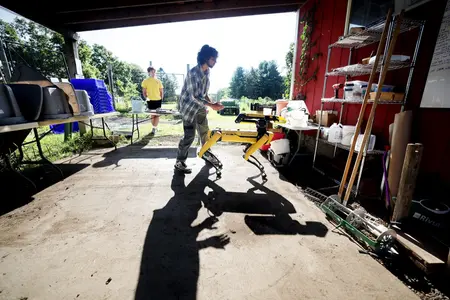 A student operates a Boston Dynamics Spot robot in a farm building