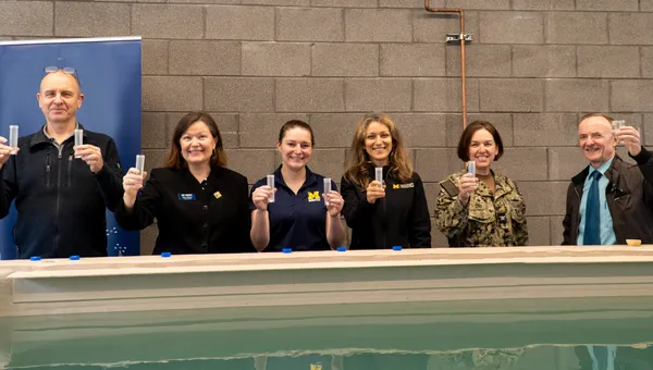 A group holds up water samples from around the country that will be poured into the new water research tank.